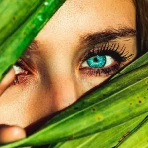kobieta z soczewką protetyczną na oku patrząca przez liście